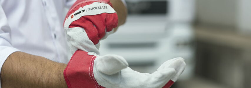 Hände mit Arbeitshandschuhen auf denen das Würth Truck Lease Logo zu sehen ist