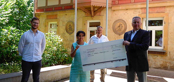 Mann übergibt Spenden Scheck an eine Frau
