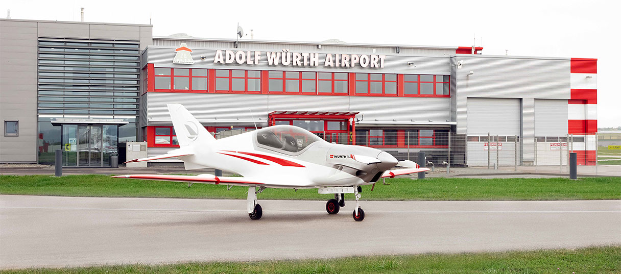 Ultraleichtflugzeug vor dem Gebäude des Adolf Würth Airport